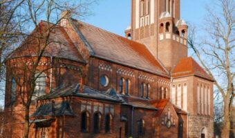 Man sieht eine alte Kirche. Die Kirche besteht aus roten Ziegel-steinen. Diese Kirche ist ein Denkmal im Land Brandenburg. Sie steht in Eichwalde im Landkreis Dahme-Spreewald.