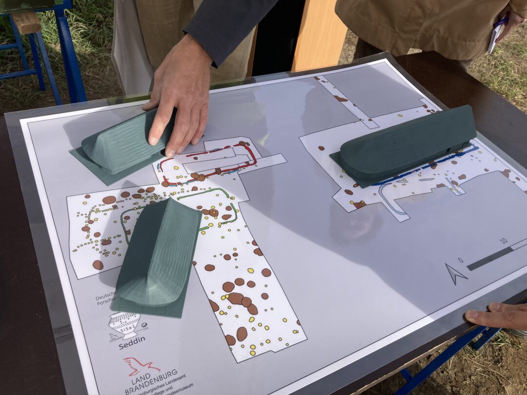 3D-gedruckte Hausmodelle auf dem Grabungsplan der aktuellen Forschungen in Seddin in der Prignitz zeigen die Struktur der bronzezeitlichen Siedlung am "Königsgrab".